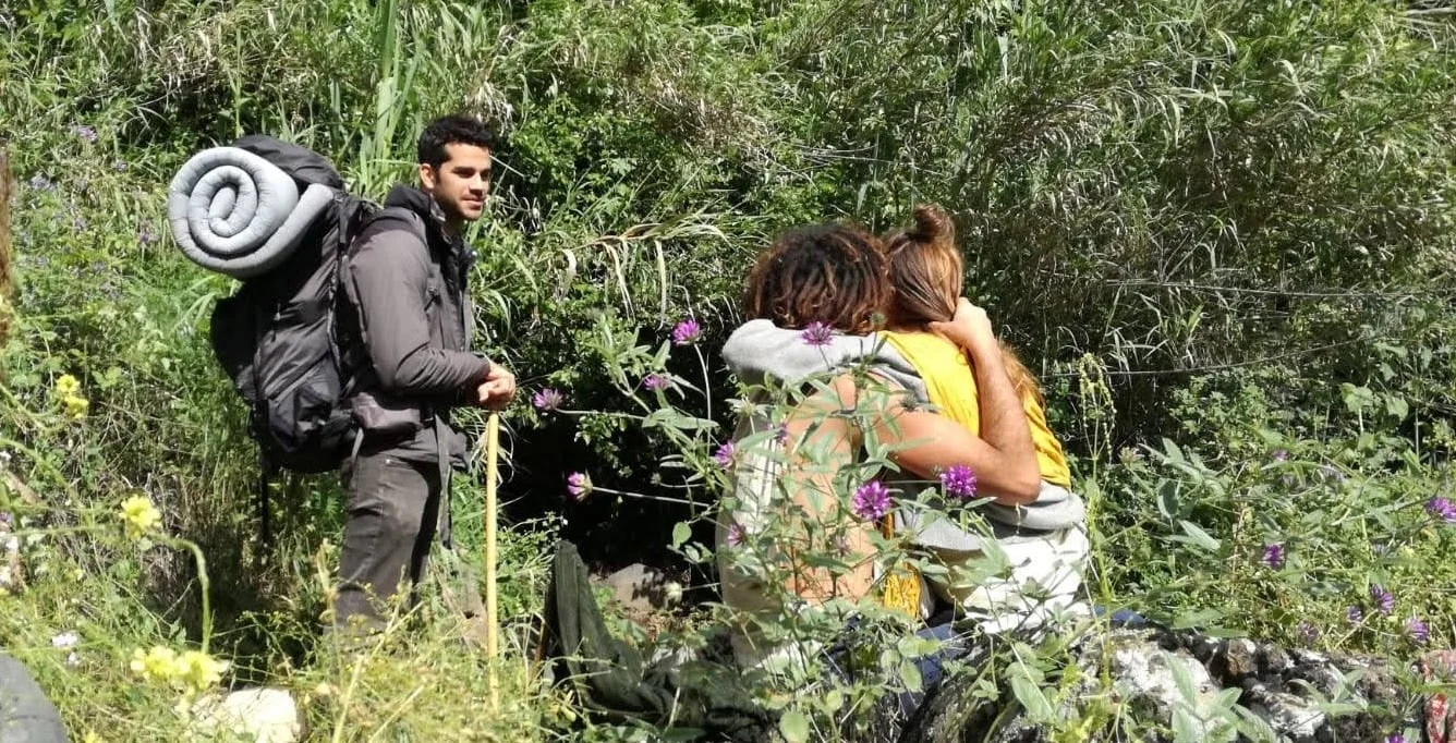 Eyal and friends sharing a hug along a green walking trail